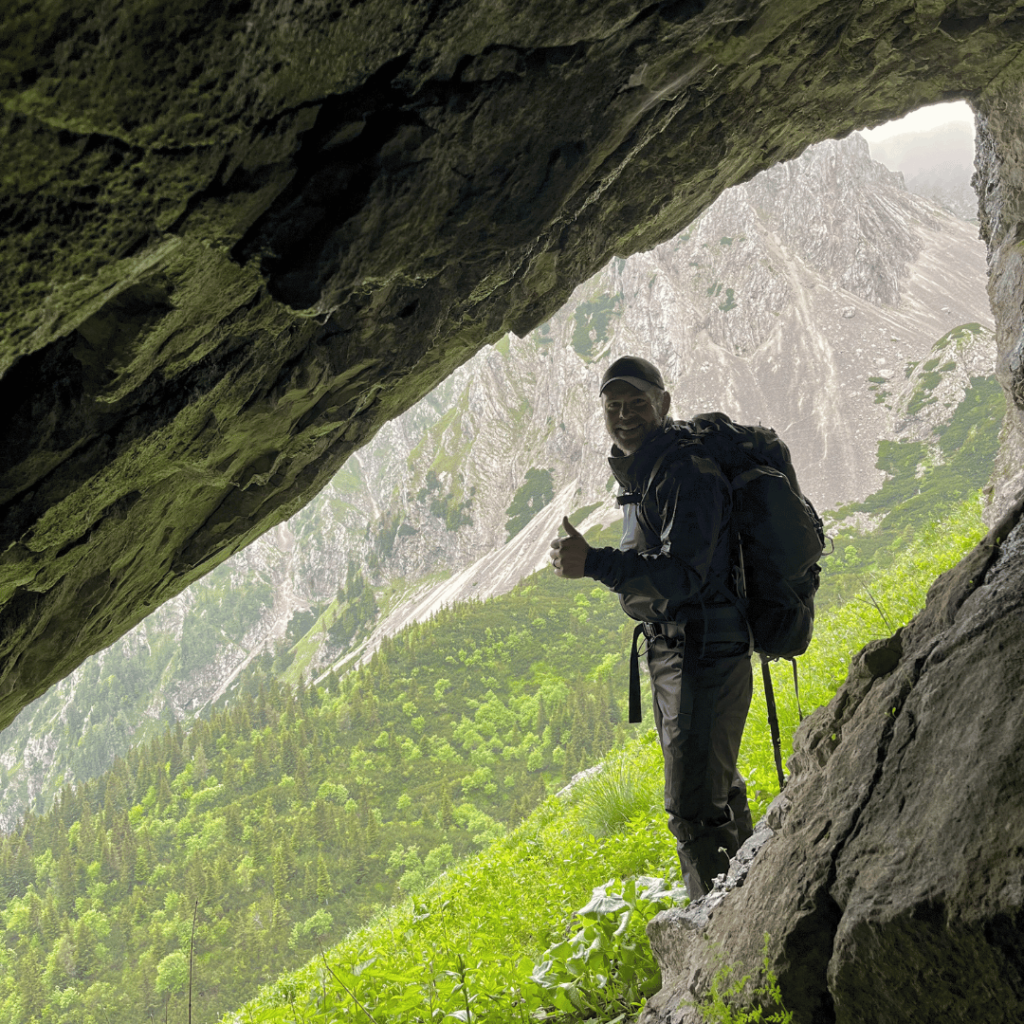 Hiker resting under a arocky overhang on the Karavanke ridge
